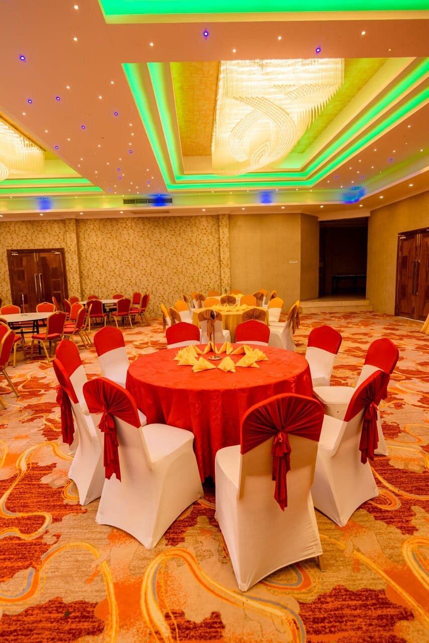 Round table with a red cloth and white chairs tied with red sashes in the Randilu Resort banquet hall